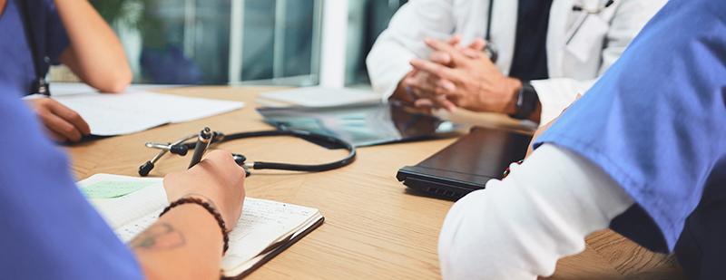 Healthcare professionals discussing patient care and reviewing medical notes during a clinical consultation